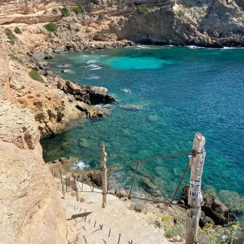 Steps leading down to a bay in Ibiza with clear water in San Antonio