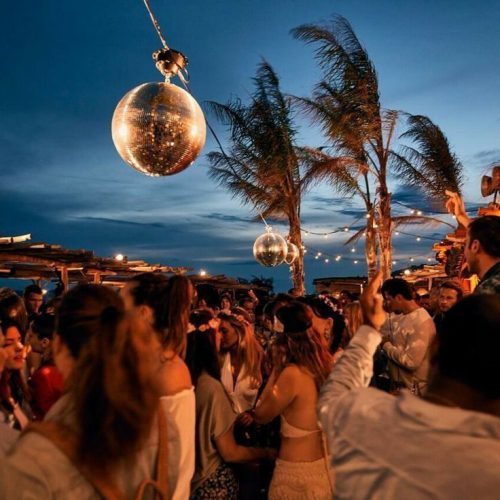 A party scene in Scorpios, Ibiza with palm trees and disco balls
