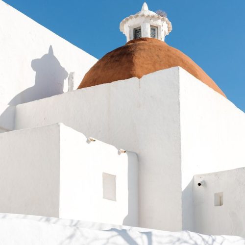 A Mediterranean house with white walls against a blue sky in Cala Llonga