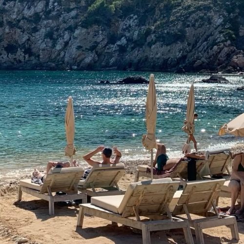 Cala Llonga beach with people sunbathing on loungers