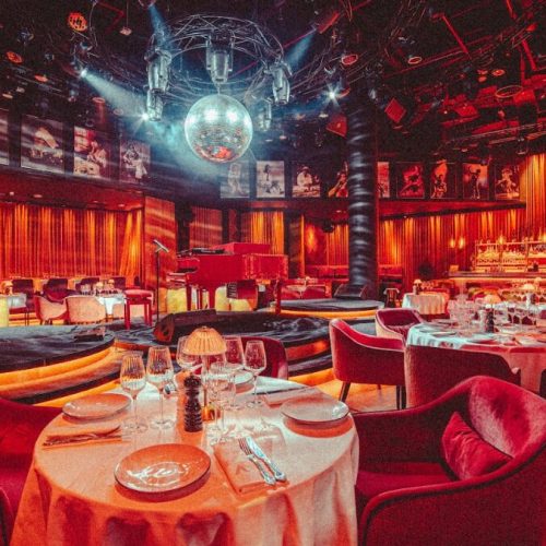 The inside of Aretha, with a round table in the foreground and a bright discoball in the back.