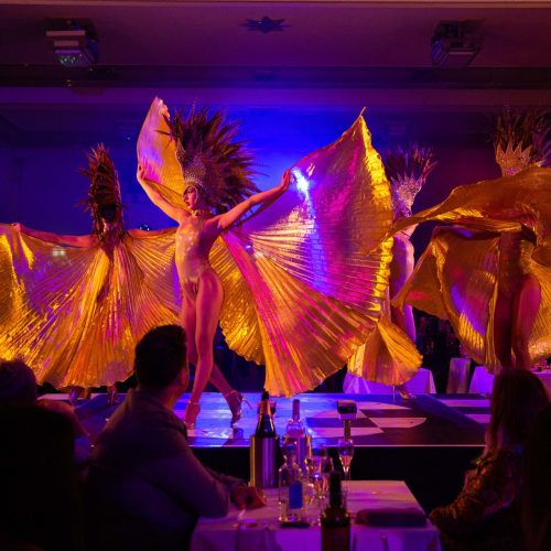 Dancers performing at The London Cabaret Club, with beautiful orange and pink costumes that flow with their movement