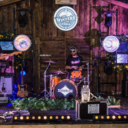 A band playing at a Christmas party at Winters of the World, with a stage decorated with festive decor