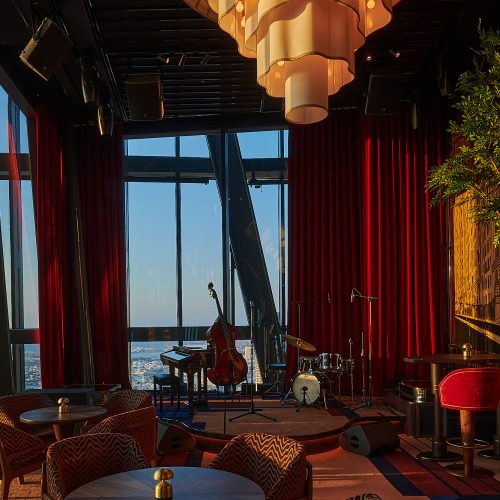 Inside of 1920 Dubai with a view of Dubai out of the window with a piano in front
