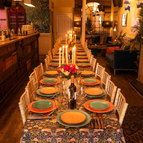 Dinner set up at The Little Blue Door with mis-matched plates and candle sticks