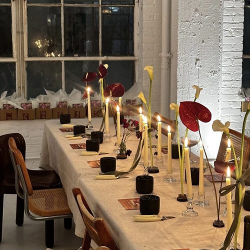 A long table set up for a dinner party with simple flowers and candles