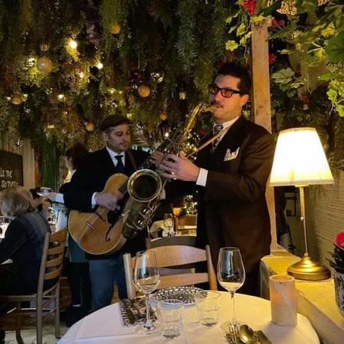 A saxophone and guitar player entertaining a dinner party