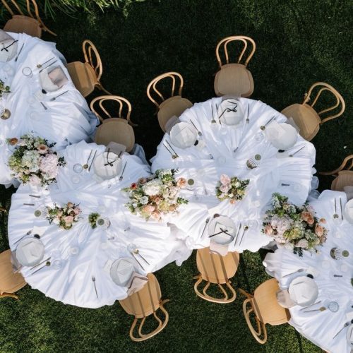 An aerial view of a dinner party set up, where multiple circular tables are set up in a row