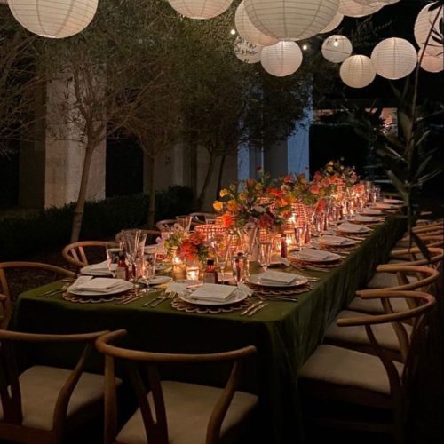 A long table set up in the evening under fairy lights