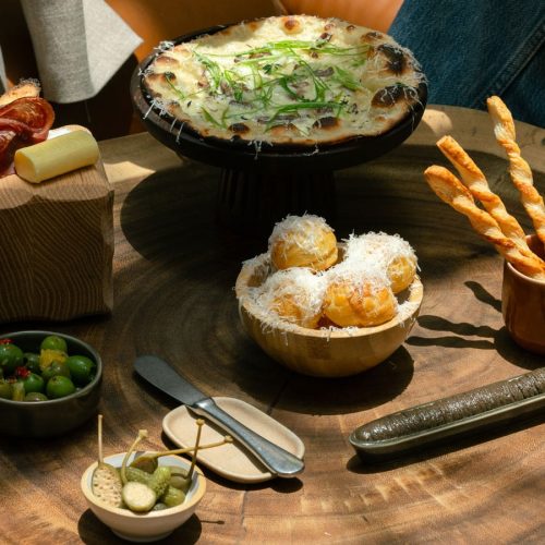 A table of food at Eugène Eugène including dough balls, breadsticks, olives, and garlic bread