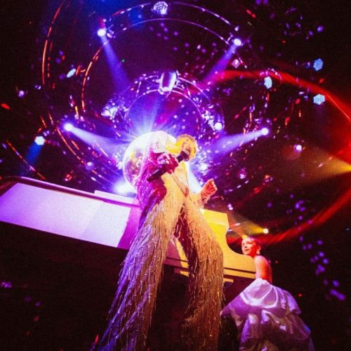 Looking up at a singer on the stage at Aretha with bright purple lights illuminating her