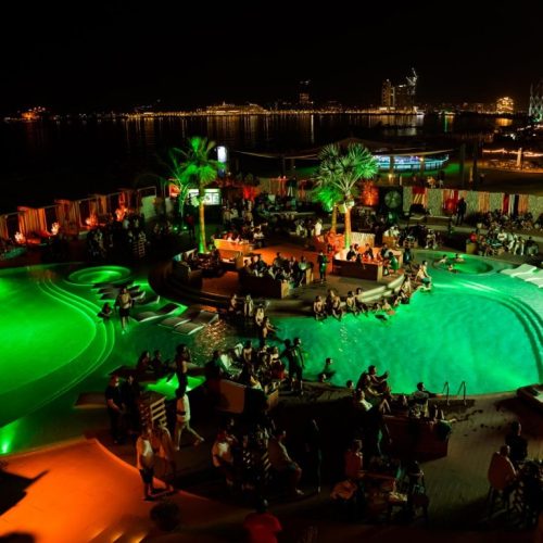 An aerial view of the pool areas at Bla Bla Dubai at night with neon green lights