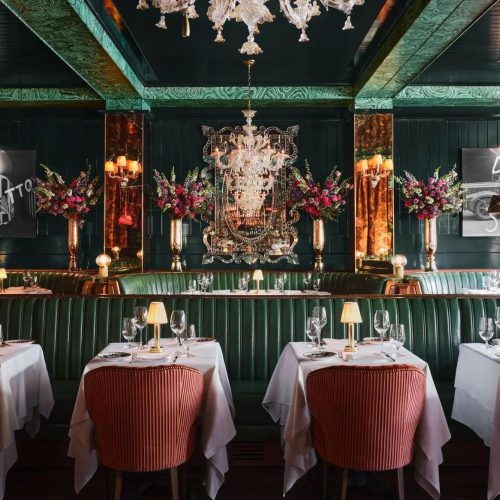 The opulent interior of Carbone, with tables dressed in white table cloths and small lamps