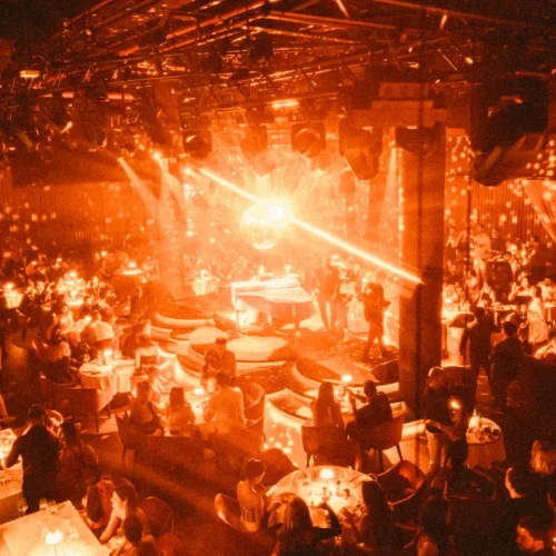Guests partying at Aretha with the disco ball reflecting bright orange lights