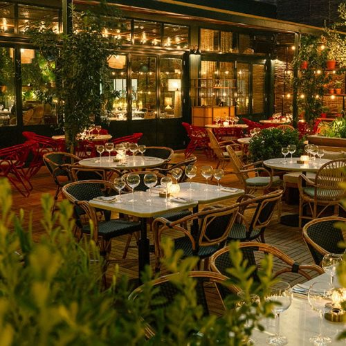 Tables laid up inside Eugène Eugène in the evening, surrounded by potted plants and dim lighting