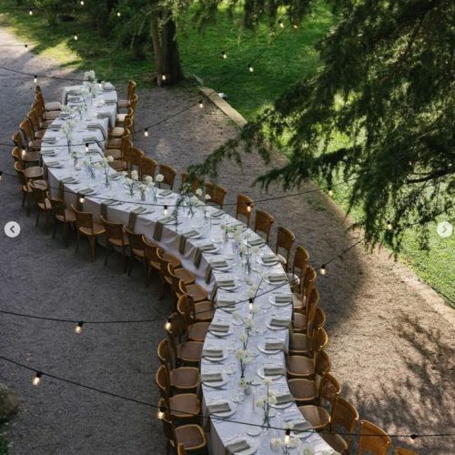 An aerial view of a long table that curves under the trees