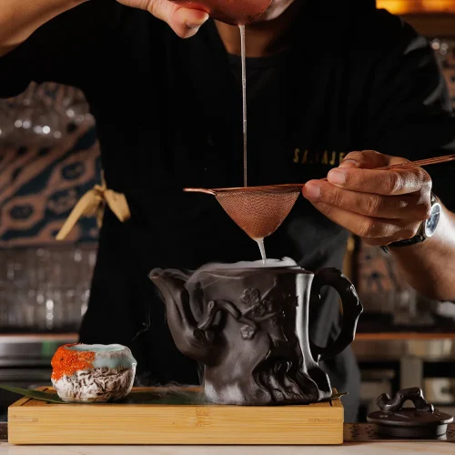 A cocktail being poured at Salvaje into a unique teapot shaped mug
