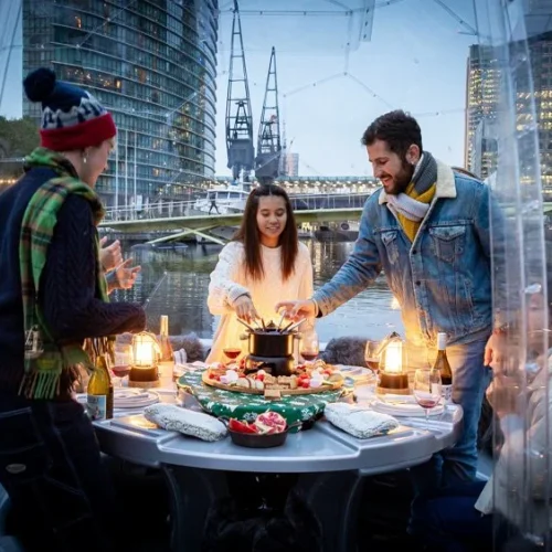 The inside of an igloo Skuna Boat, with guests standing up to use the fondu