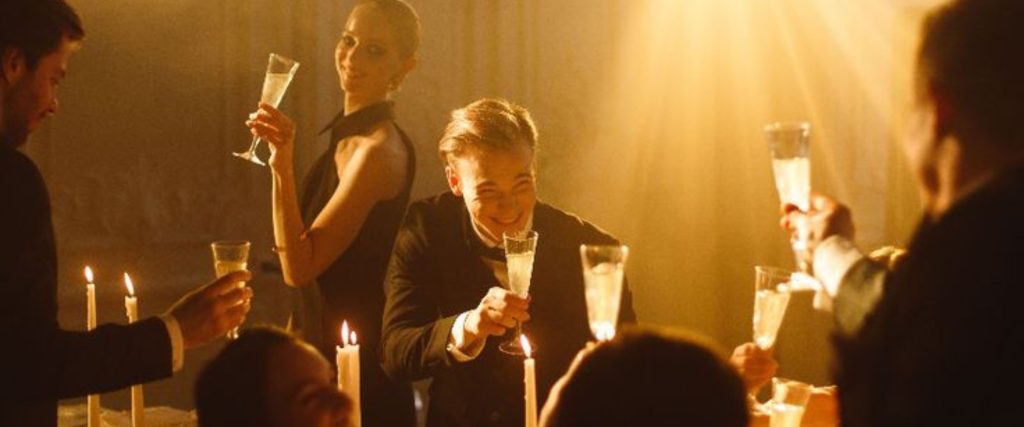 Guests at a private dinner cheering with classes of champagne in dim lighting
