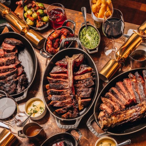 A table full of steak, sides, and Christmas decorations at Hawksmoor