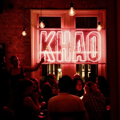 The inside of Khao Bird, which is dimly lit with a red neon 'Khao' light hung on the wall