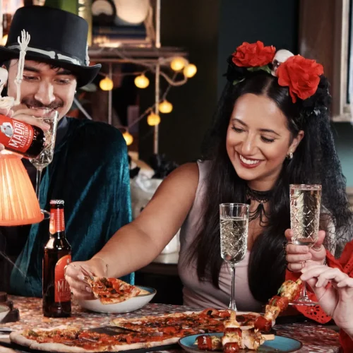 Guests dressed up in halloween costumes eating pizza and toasting with prosecco at Electric Shuffle
