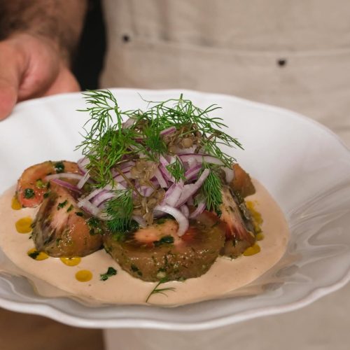 A salad being served at the newly opened Daka Daka, consisting of tomatoes, onions, and hummus