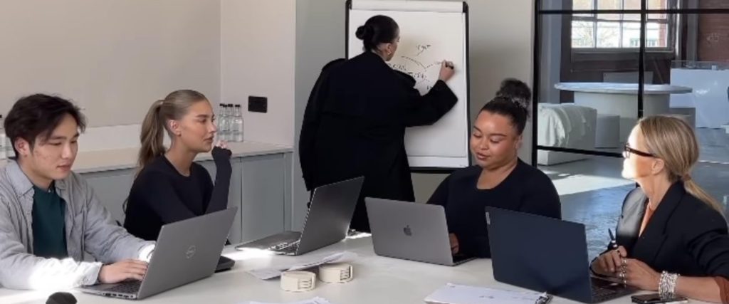 A strategy session in a meeting room, where one person is writing the teams' ideas on a white board