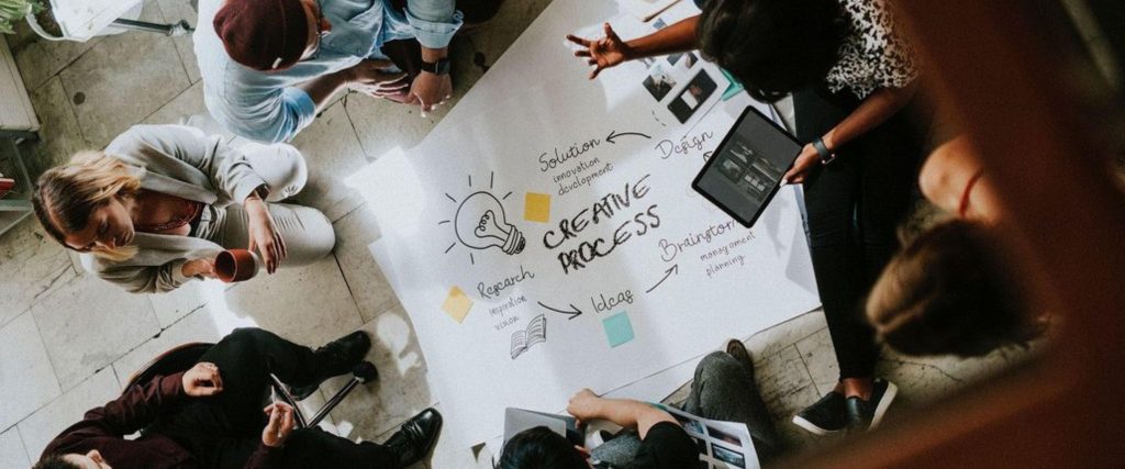 A creative strategy session at an away day, where a team is gathered around a vision board, collecting ideas