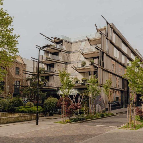 The exterior of Aethos Shoreditch, which is surrounded by trees and designed in a modern and contemporary way