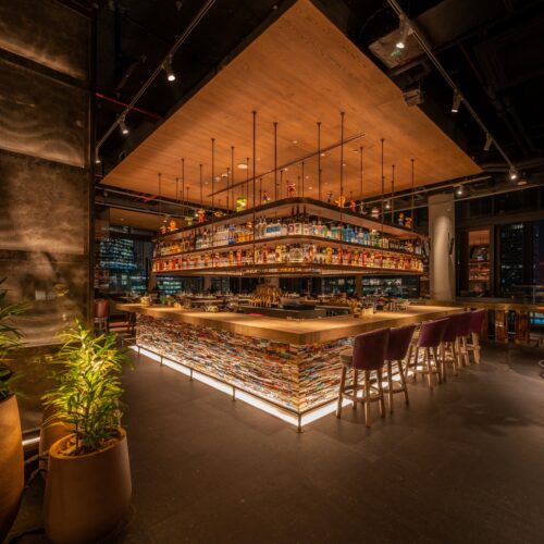The central, square bar at CLAP London, dimly and warmly lit at night for a romantic feel