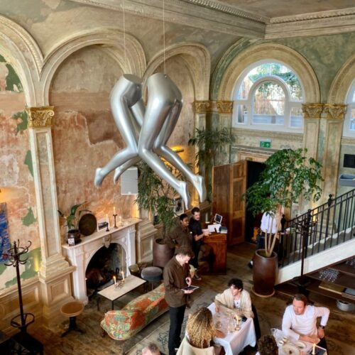 A view of Sessions Arts Club from the balcony, with a large sculpture hanging from the tall ceilings