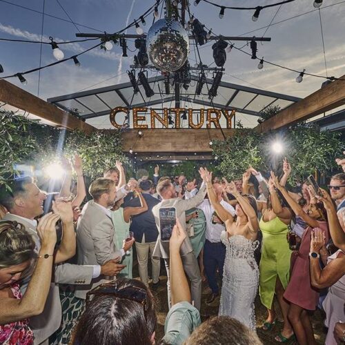 A corporate summer party at Century Club, where guests are dancing under the sunset