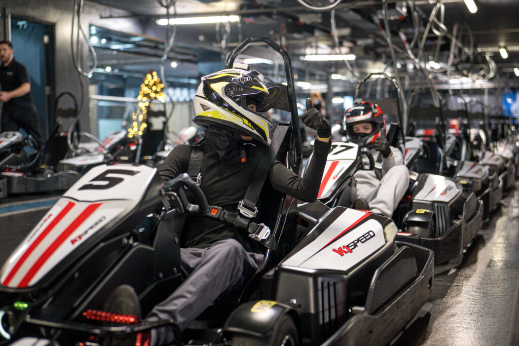 A team in race cars, ready to compete around an indoor race track at K1 Speed