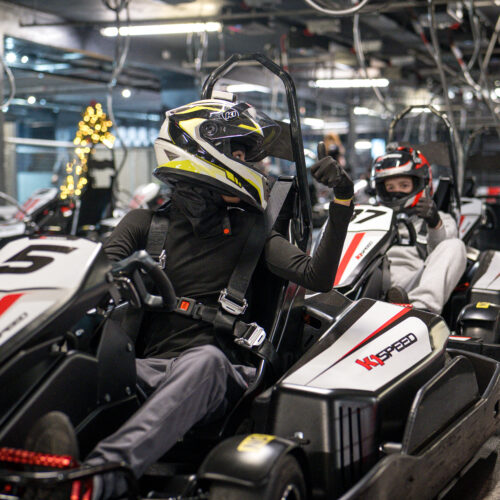 A team in race cars, ready to compete around an indoor race track at K1 Speed