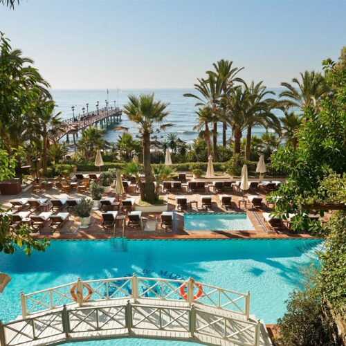 The pool area at Marbella Club Hotel on the beach front, lined with palm trees and deck chairs