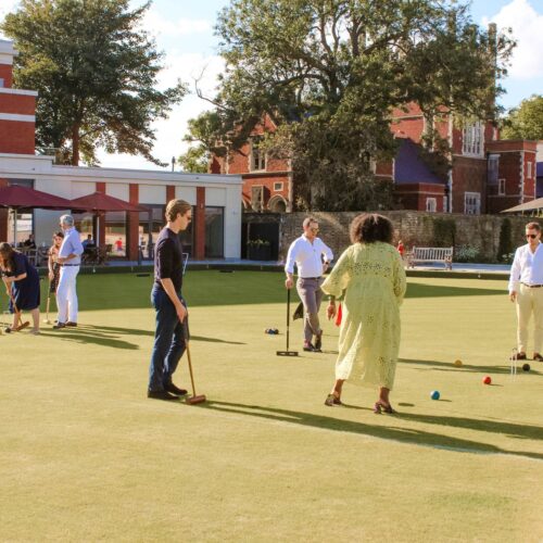 Guests playing croquet in the sun on the large lawn at Croquet & Cocktails