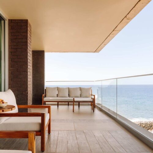 A private balcony off of a room in Saccharum, with sofas and an amazing view of the sea