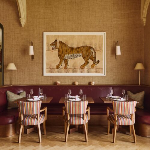 A seating area in the Lormi restaurant at Foxhills, decorated in warm tones and a piece of art featuring a tiger
