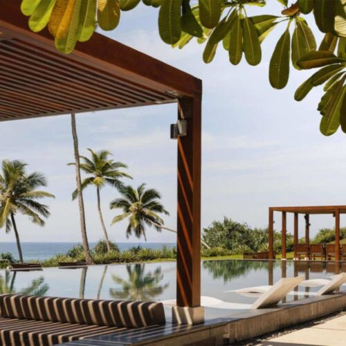 A pool at ÀNI Sri Lanka, which overlooks the sea and is surrounded by private cabanas
