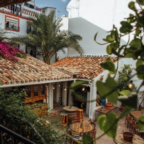 A view of some old buildings through some trees in Marbella, Spain