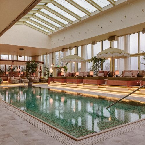 The indoor pool at Hjortviken Country Club, with sun loungers and umberells around the side