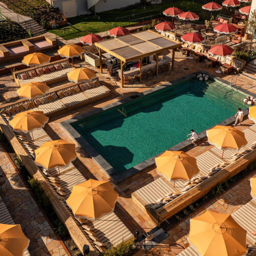 The outdoor pool at Hjortviken Country Club from above, surrounded by yellow umbrellas and loungers