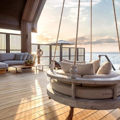 The balcony of a private bungalow in JOALI BEING, which has its own swing seat, seating area, and infinity pool